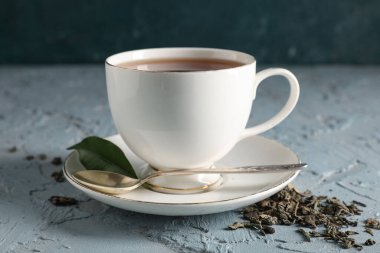 Mavi grunge arka planda bir fincan lezzetli siyah çay ve kuru yapraklar, yakın plan.