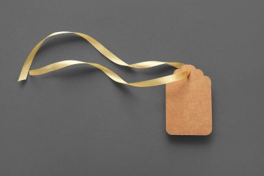 Gri arkaplanda altın kurdeleli boş kağıt etiket