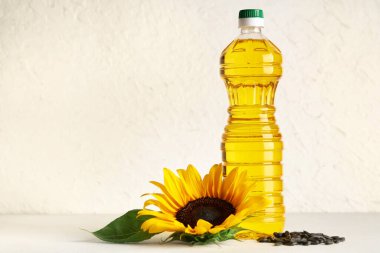 Ayçiçekli bir şişe yağ ve ışık arkaplanda tohumlar