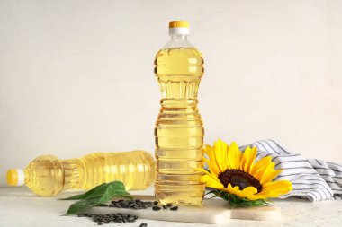 Ayçiçekli yağ şişeleri ve ışık arka planında tohumlar