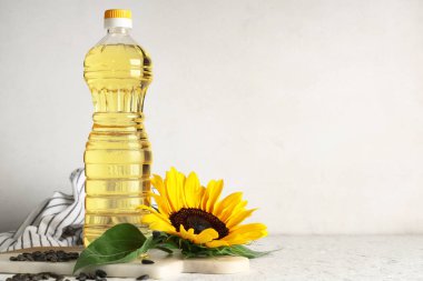Ayçiçekli bir şişe yağ ve ışık arkaplanda tohumlar