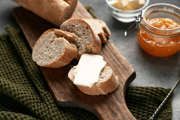 Tereyağlı dilimlenmiş ekmek ve bir kavanoz kayısı reçeli gri grunge arka planda