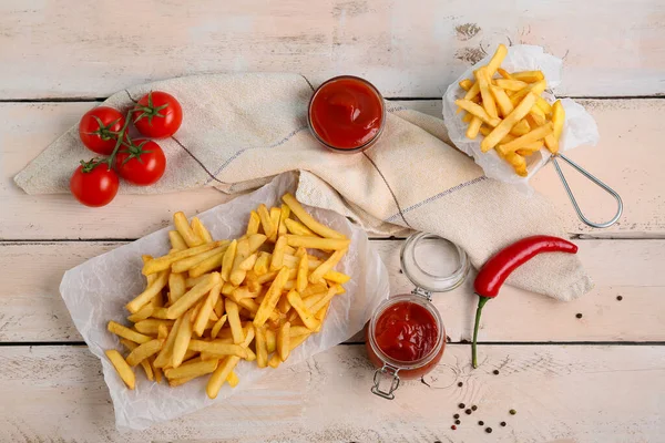 Lezzetli patates kızartması, domates, kırmızı biber ve hafif ahşap arka planda ketçap kavanozu olan kızartma sepeti.