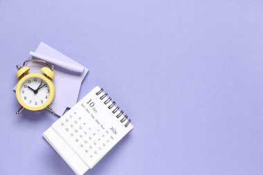 Alarm saati ve mor arkaplan üzerindeki yapışkan notlarla takvim