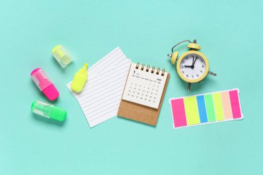 Turkuaz arkaplanda alarm saati, kağıt kağıtlar, işaretleyiciler ve çıkartmalarla takvim