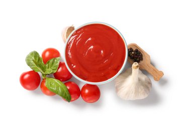 Bir kase lezzetli domates sosu ve beyaz arka planda farklı baharatlar.