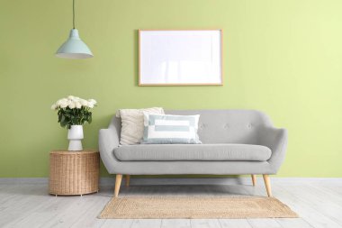 İçinde kanepe, sepet ve vazoda beyaz güller olan oturma odası.