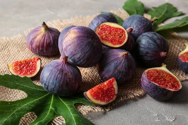 Gri arka planda taze incir ve yapraklar, yakın plan.