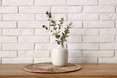 Okaliptüs dalları olan vazo beyaz tuğla duvarın yanındaki odada.