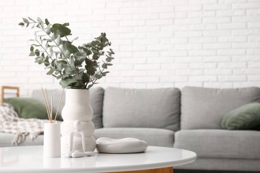 Okaliptüs dallı vazo, heykel ve aroma çubukları odanın içindeki masada, yakın plan.