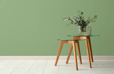 Okaliptüs dalları olan vazo yeşil duvarın yanındaki odada.