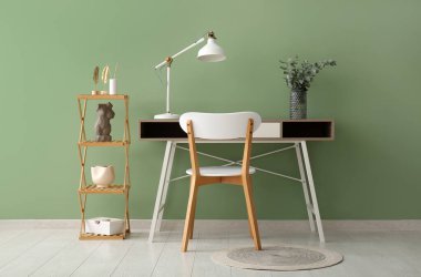 Yeşil duvarın yanındaki vazoda lamba ve okaliptüs dalları olan işyeri.