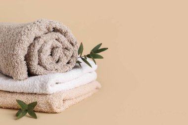 Temiz yumuşak havlular ve bej arka planda yeşil dallar, yakın plan