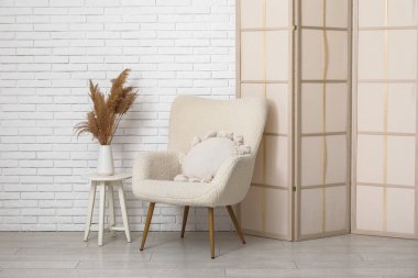 Katlanan ekran, koltuk ve vazo, beyaz tuğla duvarın yanında otlar, yakın plan.