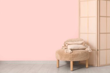 Katlanan ekran ve pouf pembe duvarın yanında yastıklar, yakın çekim