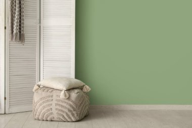Katlanan ekran, pouf ve yastık odada yeşil duvarın yanında, yakın plan
