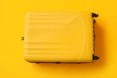 Sarı arka planda paketlenmiş bavul, yakın plan