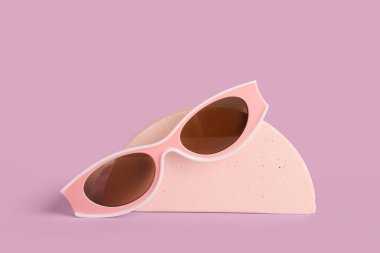 Leylak arkaplanda şık güneş gözlükleri ve alçı podyum, yakın plan.