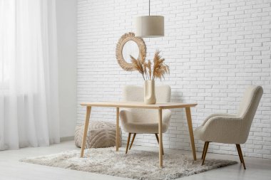 Beyaz tuğla duvarın yanında masası ve koltuğu olan yemek odasının içinde.