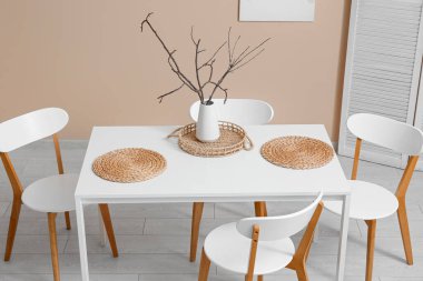 Yemek odasının içinde masa ve bej duvarın yanında sandalyeler.