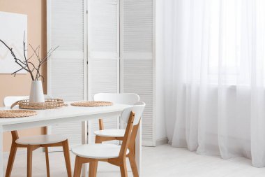 Yemek odasının içinde masa, sandalye ve pencerenin yanında katlanan ekran var.