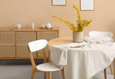 Yemek odasının içinde çekmeceler, masa ve bej duvarın yanındaki sandalyeler.