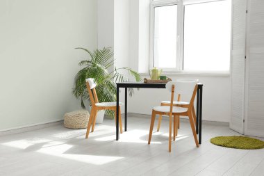 Yemek odasının iç tarafındaki pencere kenarındaki masa ve sandalyeler.