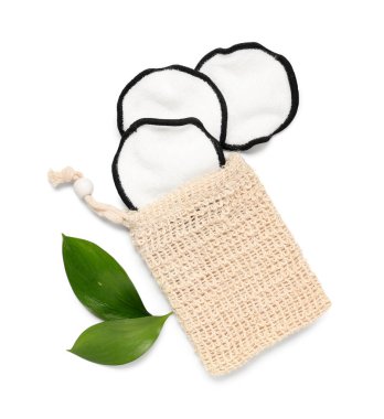 Poşet, yeniden kullanılabilir pamuk pedler ve yeşil yapraklar beyaz arkaplanda izole edilmiş