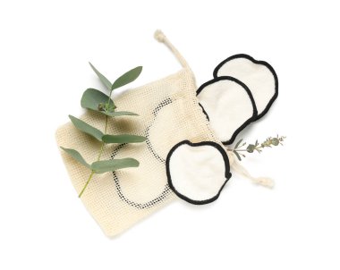 Yeniden kullanılabilir pamuk yastıklı çanta ve beyaz arkaplanda izole edilmiş yeşil dallar