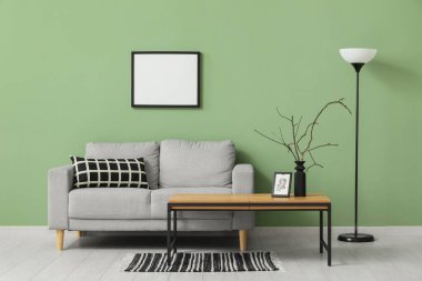 Oturma odasının iç tarafındaki yeşil duvarın yanındaki sehpa ve kanepe.