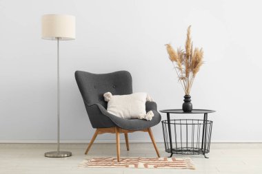 Kahve masası, koltuk ve zemin lambası odanın içindeki beyaz duvarın yanında.