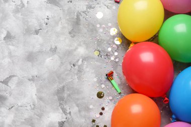 Hava balonlu kompozisyon, şenlikli pipo ve gri grunge arka planda konfeti, yakın plan.