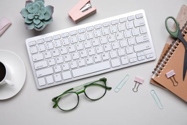 Beyaz arkaplanda klavye, gözlük ve kırtasiye malzemesi ile kompozisyon, yakın plan