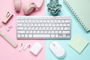 Renk arkaplanı üzerine klavye, fare, kulaklık ve kırtasiye malzemesi kompozisyonu, yakın plan