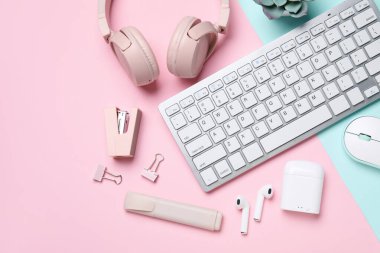 Renk arkaplanı üzerine klavye, fare, kulaklık ve kırtasiye malzemesi kompozisyonu, yakın plan