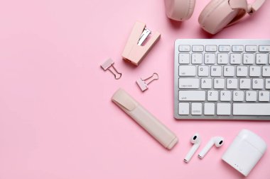 Pembe arka planda klavye, kulaklık ve kırtasiye malzemesi ile kompozisyon, yakın plan