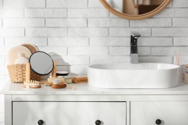 Masaj fırçaları, banyo malzemeleri ve lavabonun yanındaki masada ayna.