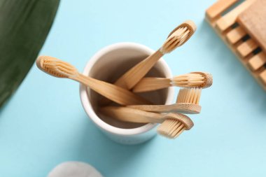 Mavi zemin üzerinde ahşap diş fırçası olan seramik cam, yakın plan.