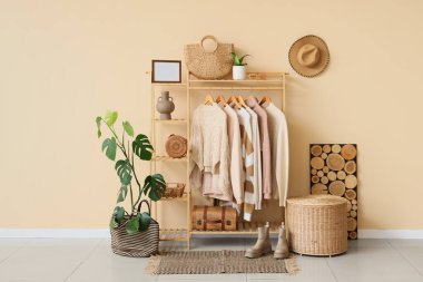 Masa, ahşap raf, şık kıyafetler ve aksesuarlar, odanın içindeki bej duvarın yanında.