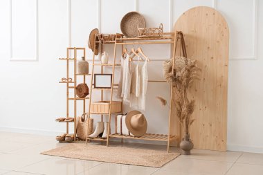 Odanın içinde beyaz duvarın yanında şık giysileri olan ahşap raf ve raf ünitesi.