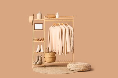 Pouf ve ahşap raf, bej arka planda şık kıyafetler.