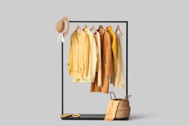 Gri arka planda şık kıyafetler ve aksesuarlarla siyah askılar.