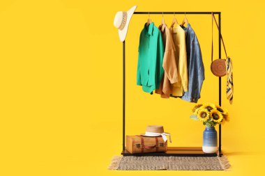 Şık elbiseli siyah raf, aksesuarlar ve sarı arka planda ayçiçekli vazo.