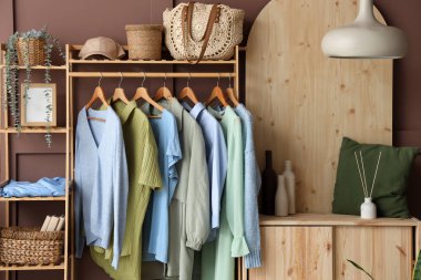 Raflar ve raflar kahverengi duvarın yanında şık kıyafetler, yakın plan.