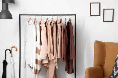 Beyaz duvarın yanında asılı giysilerle dizilin, kapatın.