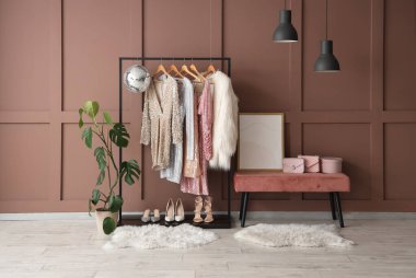 Rafta, bankta giysiler, aksesuarlar ve kahverengi duvarın yanındaki disko topu.