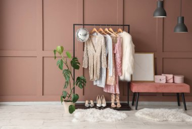 Rafta, bankta giysiler, aksesuarlar ve kahverengi duvarın yanındaki disko topu.