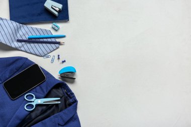 Cep telefonlu farklı kırtasiye malzemeleri ve beyaz arka planda şık okul üniforması.