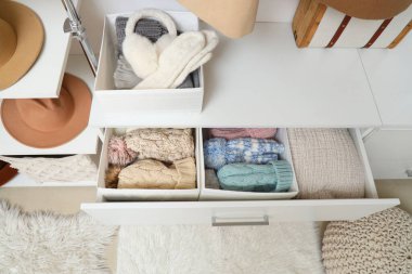 Üst kattaki dolapta organize kış kıyafetleri olan açık çekmece.