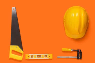 El testereli sarı şapka, ruh seviyesi ve turuncu arka planda klemp.